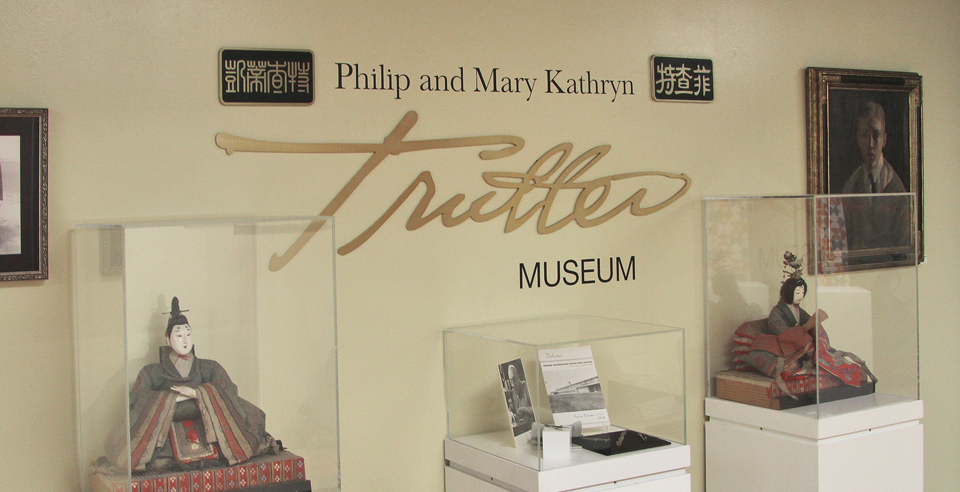 Three pieces of art in display cases in front of a wall that says Philip and Mary Kathryn Trutter Museum.