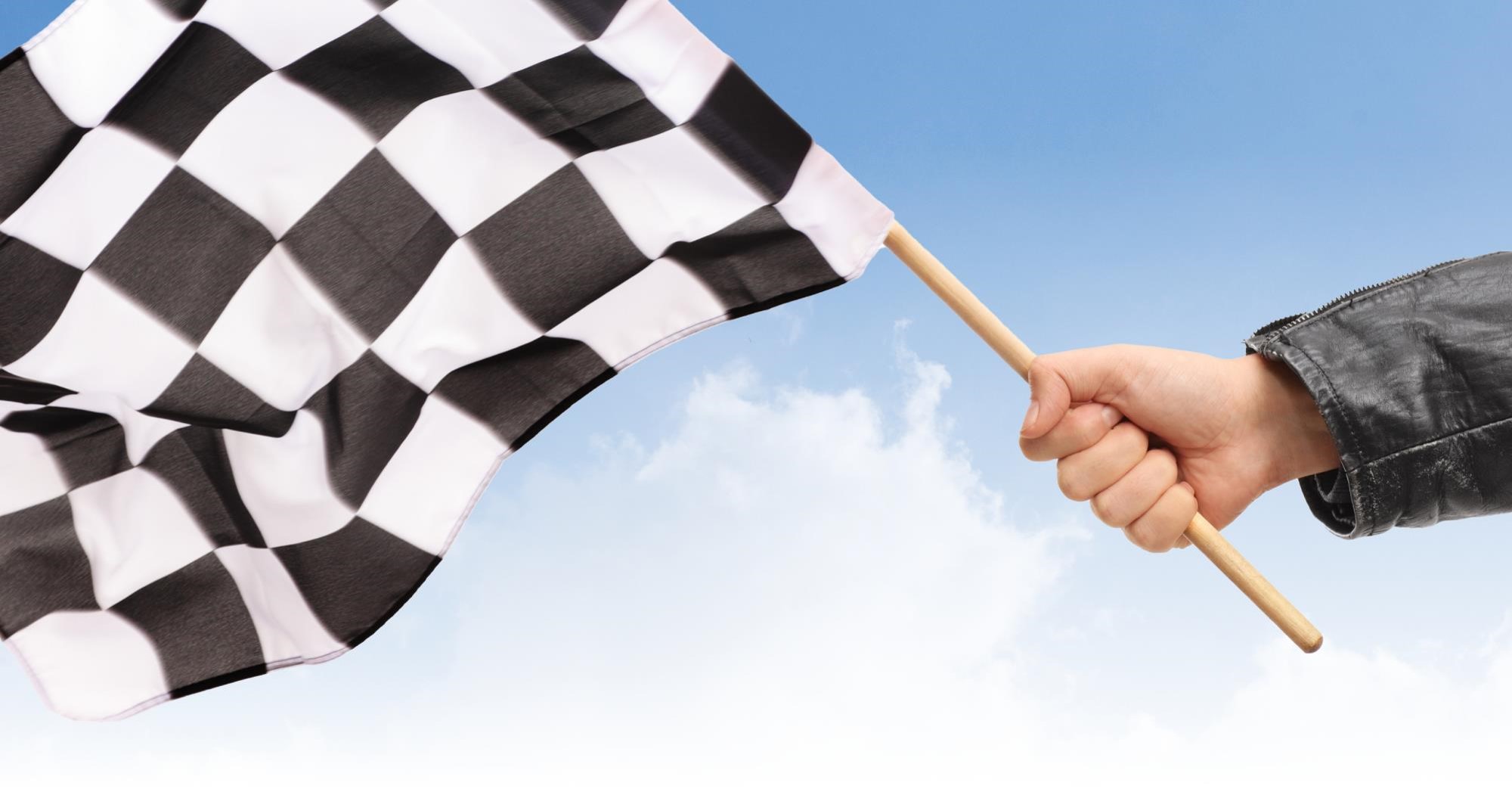 A hand waving a checkered race flag.