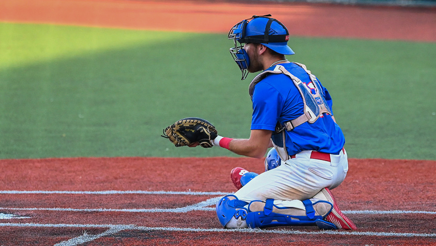 A Loggers catcher falls to the ground on one knee and readies to catch a ball.