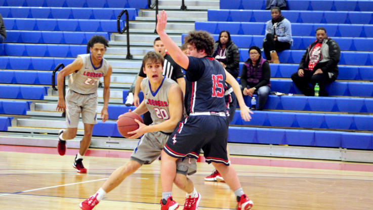 An LLCC men's basketball player dodges an opponent while holding onto the ball. 