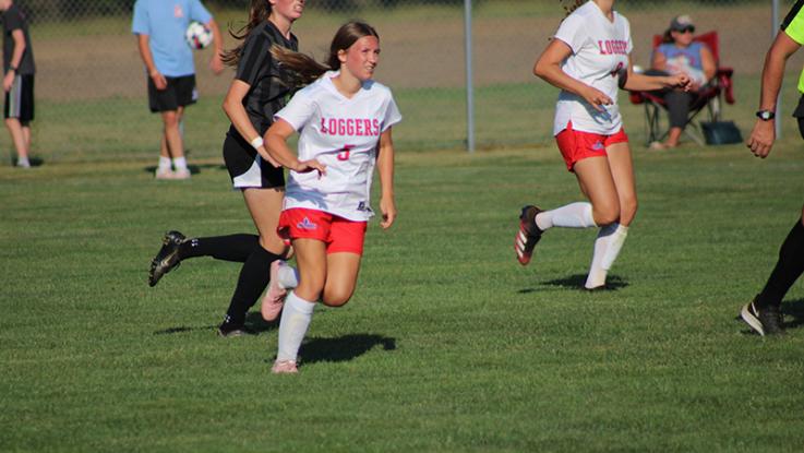 Two LLCC women's soccer players run across the field. 