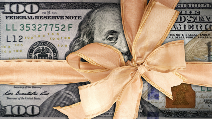 An American $100 bill gift wrapped in gold ribbon.