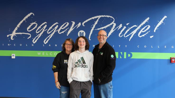 Mom, dad and son posing near the Logger Pride wall.