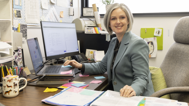 A college professor sits at her desk to prep coursework. 