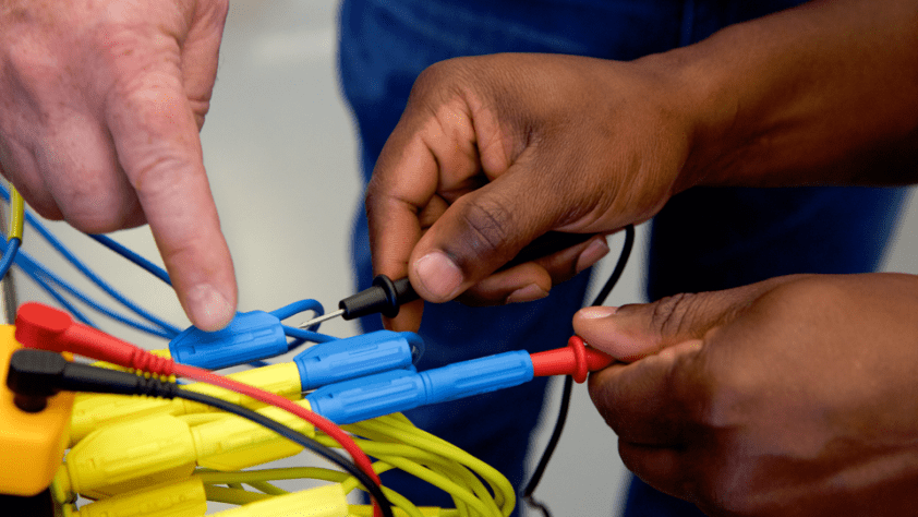 Two sets of hands are shown working with wires.