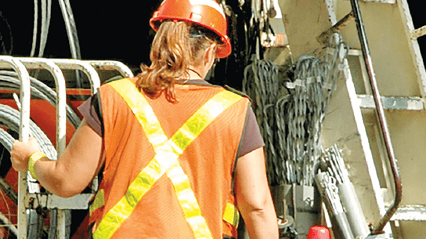 The back of a woman and she climbs stairs to an electrical unit.