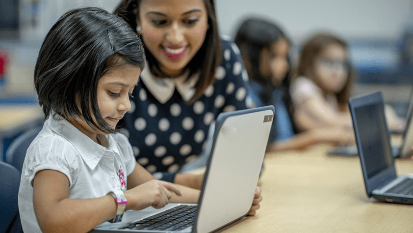 Teacher in classroom with students on laptops