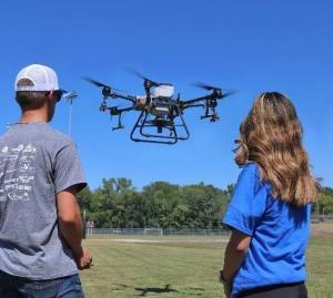 Students watch as a large drone takes flight.