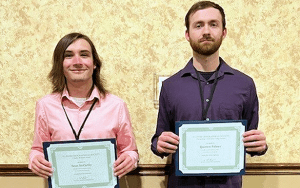 Two male students pose for a photo holding an award certificate.