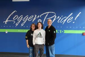 Mom, dad and son posing near the Logger Pride wall.